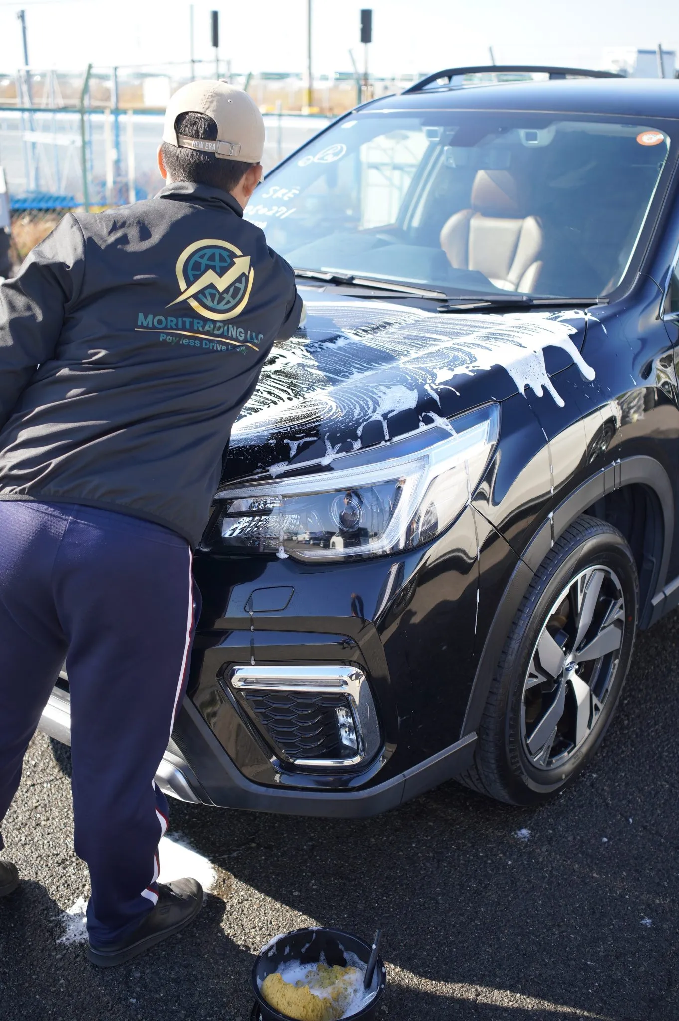 A MORITRADING staff member hand-washing a vehicle before export
